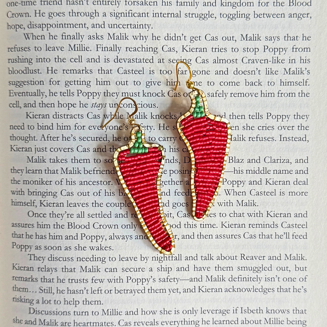 Red chili pepper earrings on a book page
