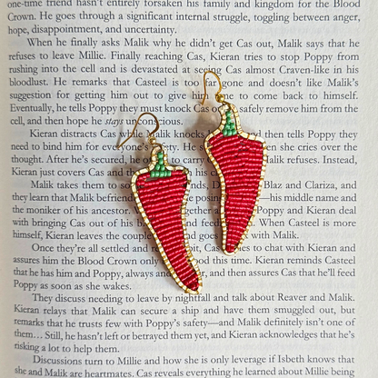 Red chili pepper earrings on a book page